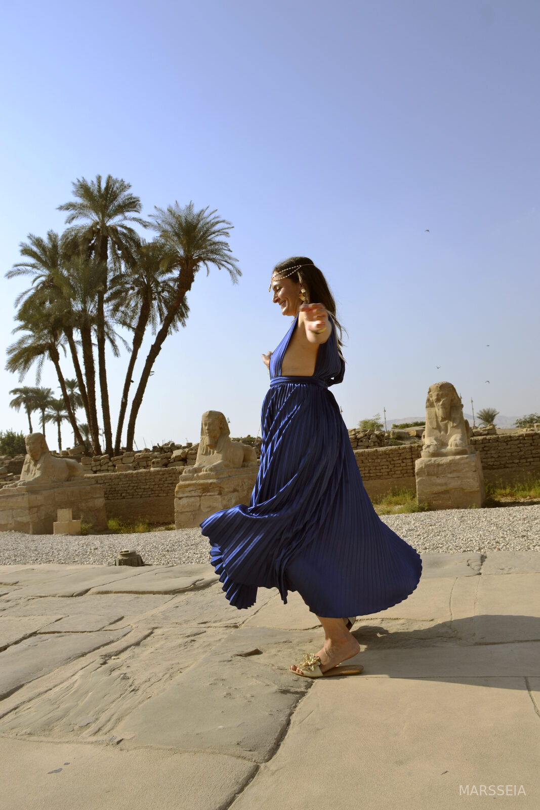 A woman in a blue dress walking among the sphinxes, Luxor